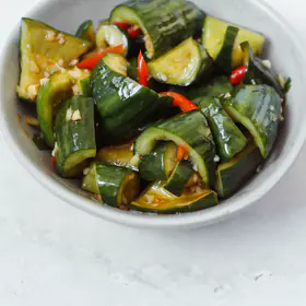 Smashed cucumber with red chili in a white bowl