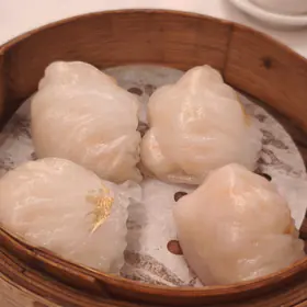 Four translucent shrimp dumplings in a bamboo steamer