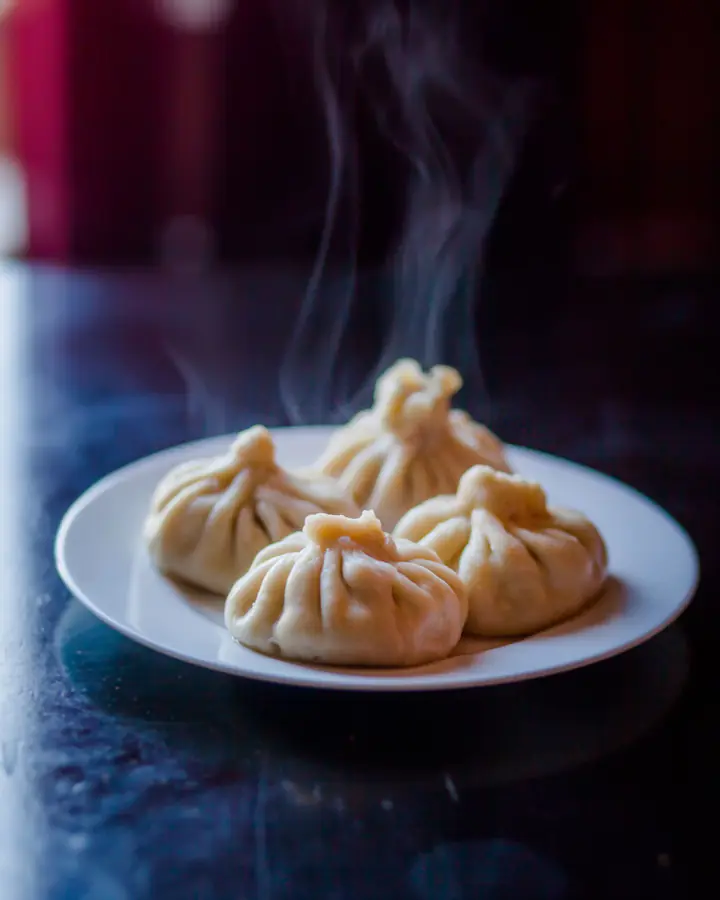 Steam rising from a plate of freshly steamed dumplings