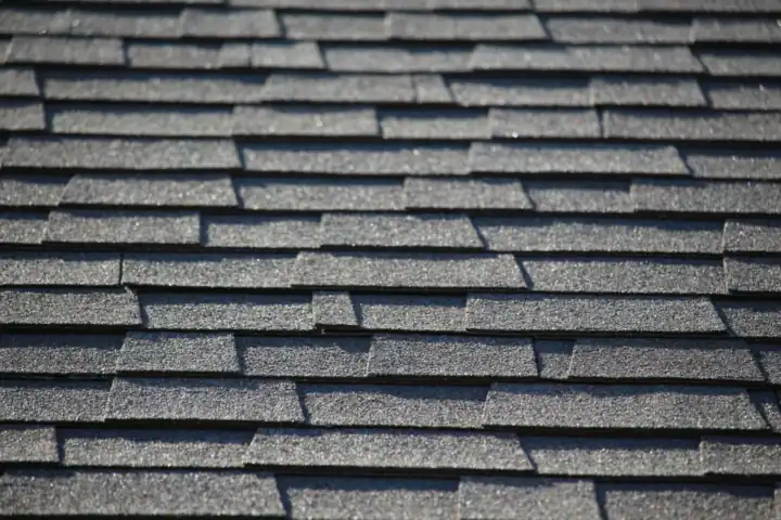 Close-up of grey asphalt shingles laid in staggered rows.